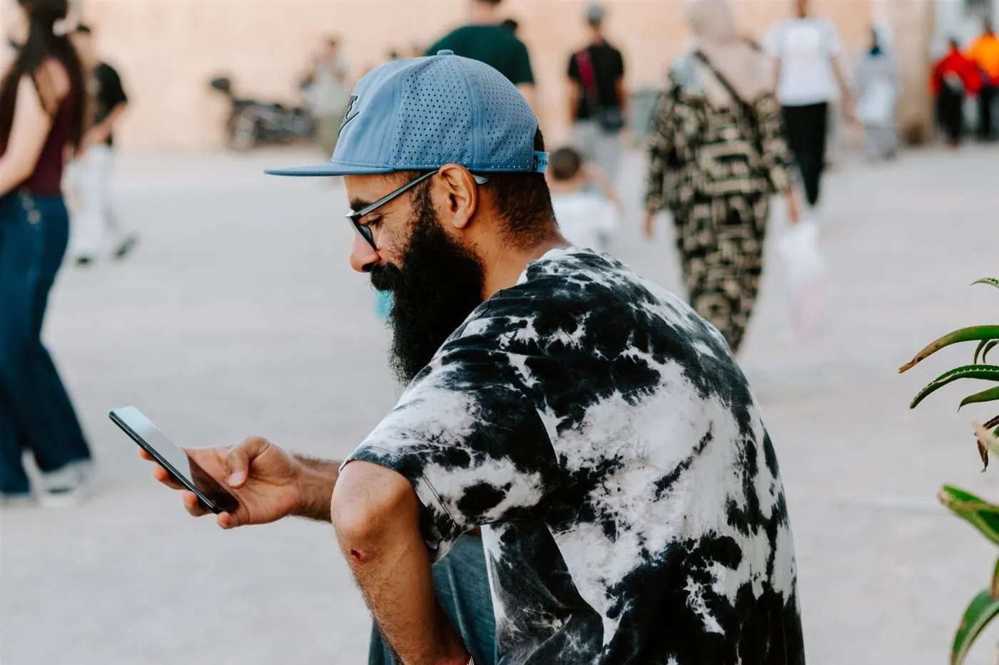 Homme barbu en casquette qui consulte son smartphone dans une rue de Rabat