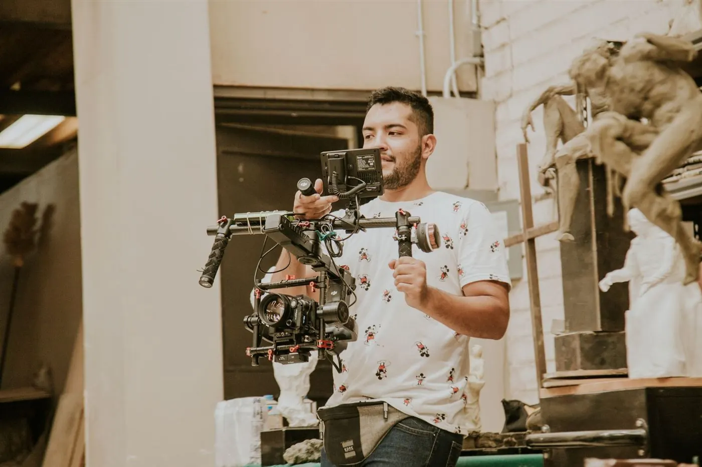 Vidéaste en chemise blanche à motifs qui tient une caméra montée sur stabilisateur